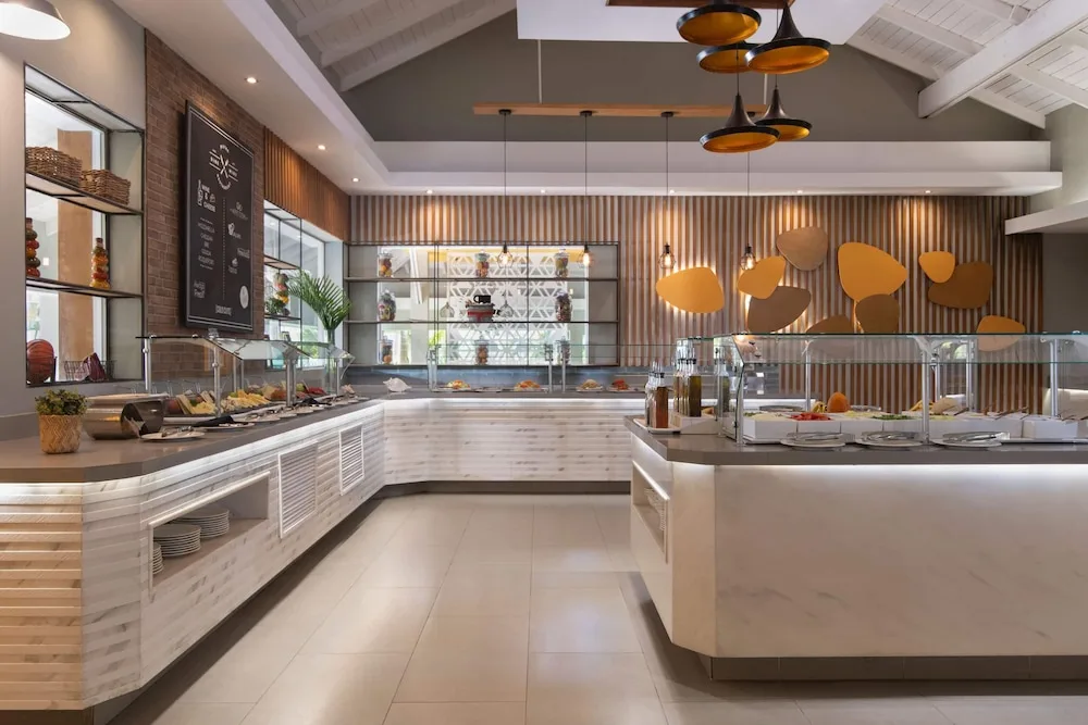 A buffet dining area with serving counters is set inside Wyndham Alltra Samana Resort.