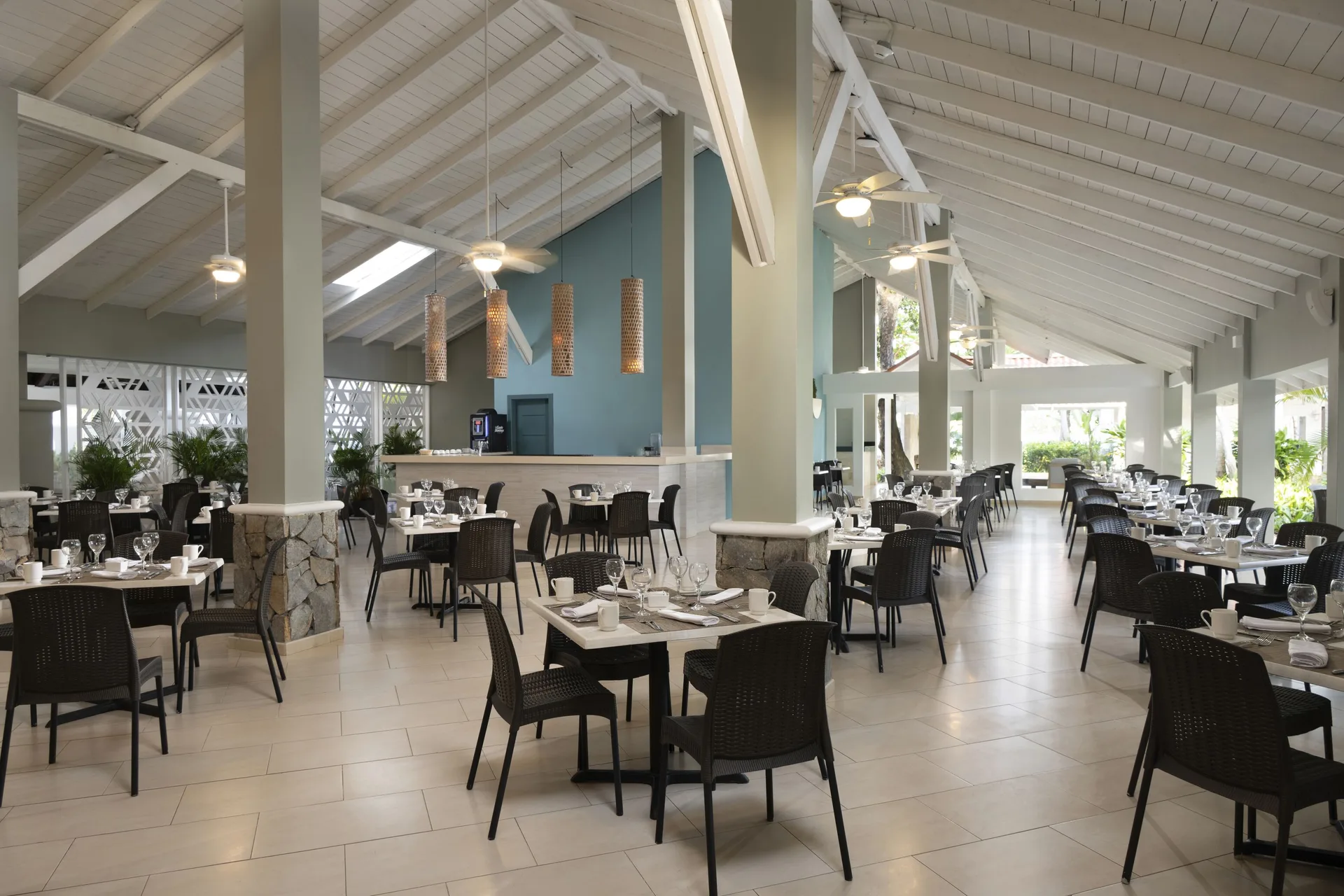Open-air dining room with black chairs and white ceiling at Wyndham Alltra Samana Resort.