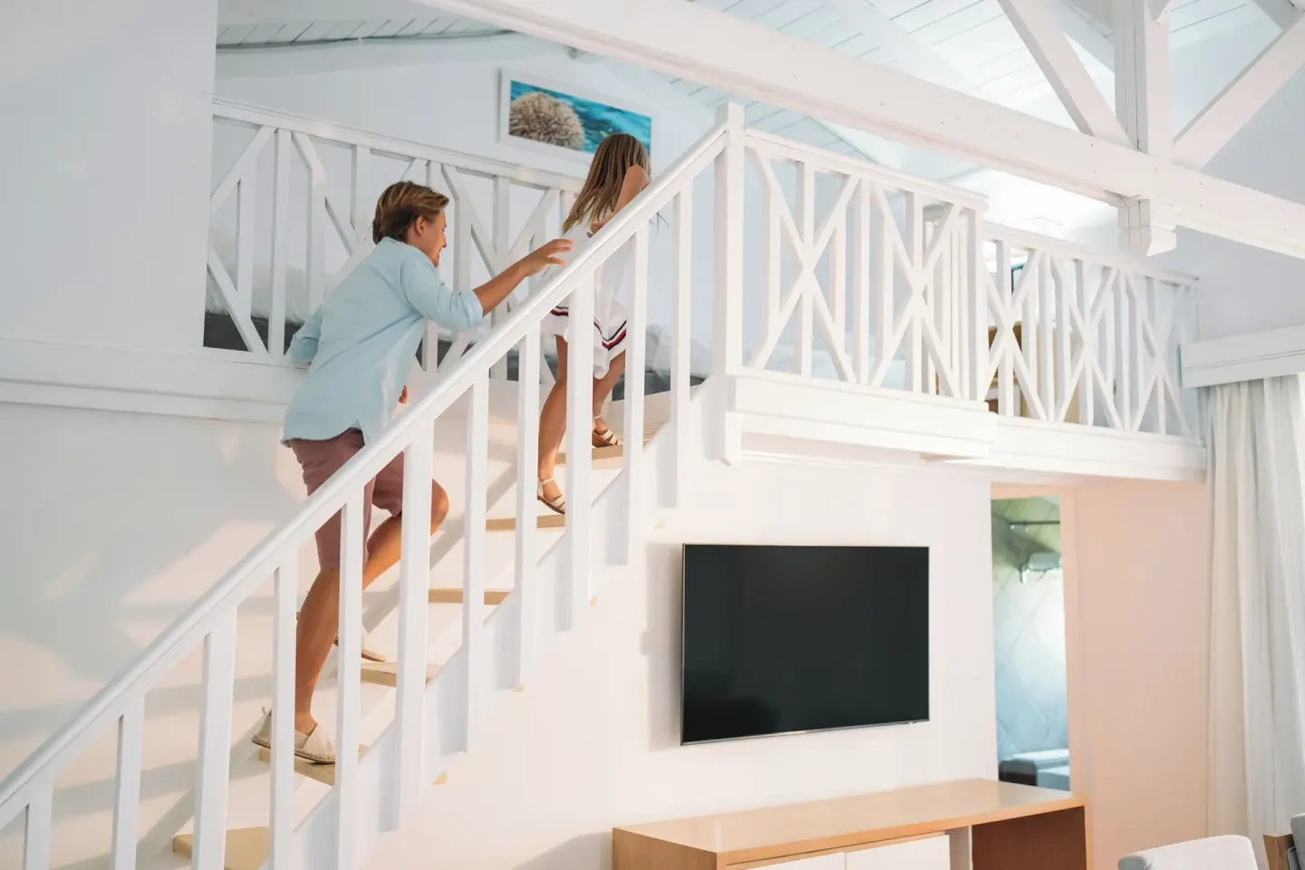 Guests climb the loft stairs above the TV in a Club Bungalow Garden View room at Wyndham Alltra Samana Resort.