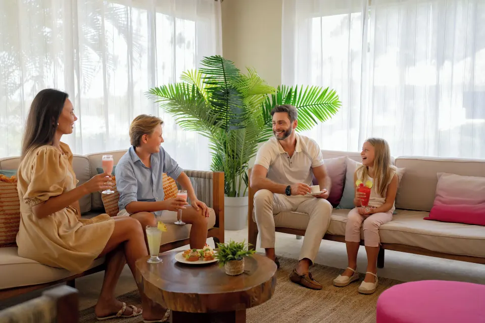 Family seated with drinks in the Club lounge at Wyndham Alltra Samana Resort.