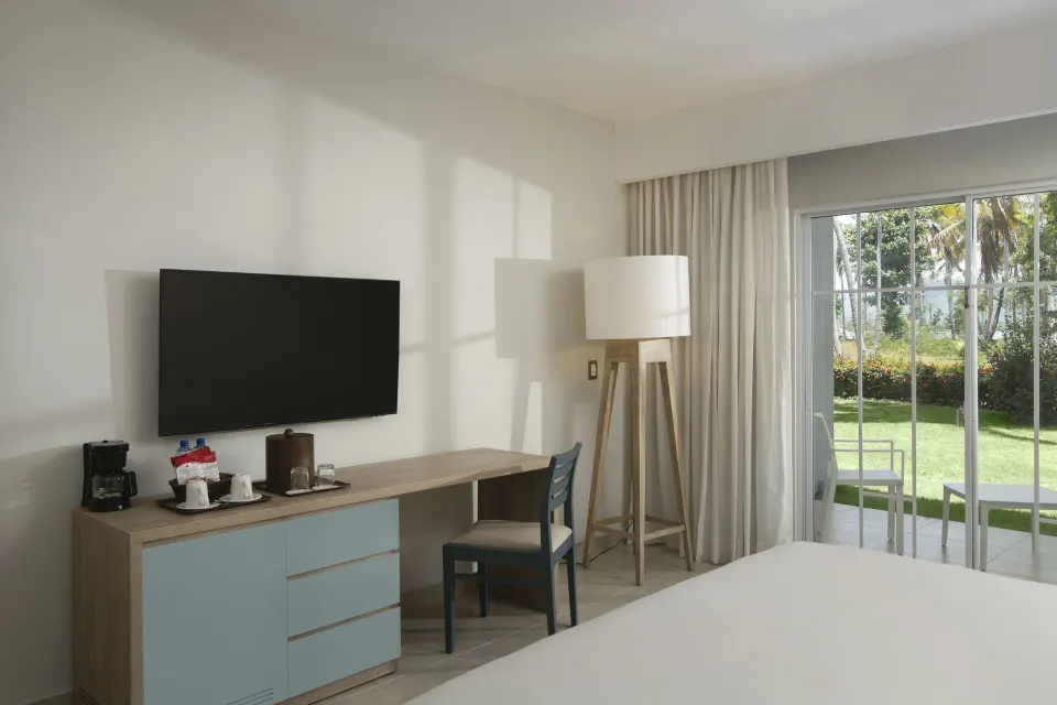 Standard Room Garden View desk, TV and patio doors at Wyndham Alltra Samana Resort.