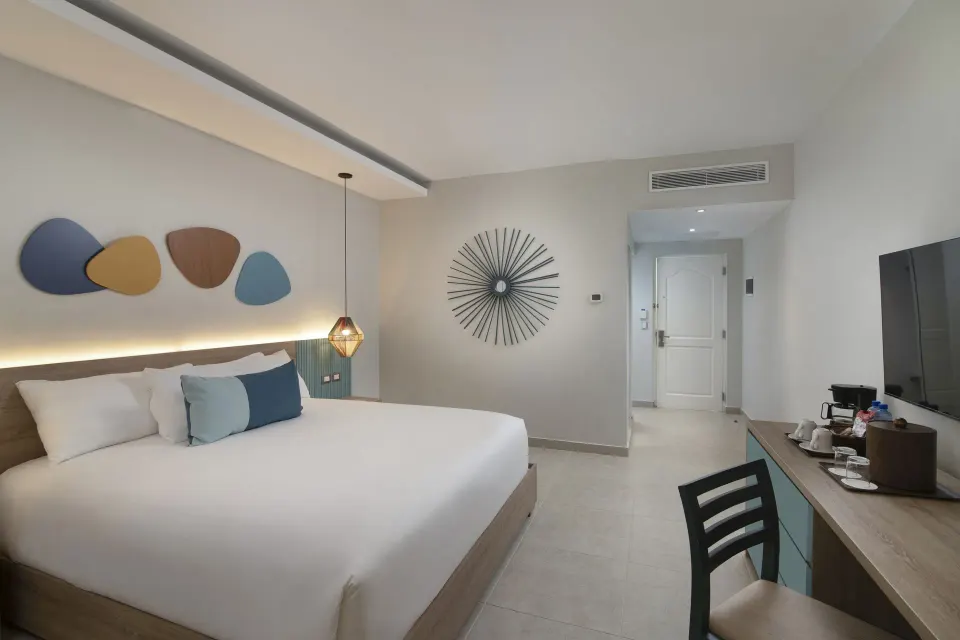 Standard Room Garden View king bed and entry wall art at Wyndham Alltra Samana Resort.