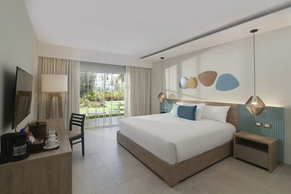 Standard Room Garden View king bed and patio doors at Wyndham Alltra Samana Resort.