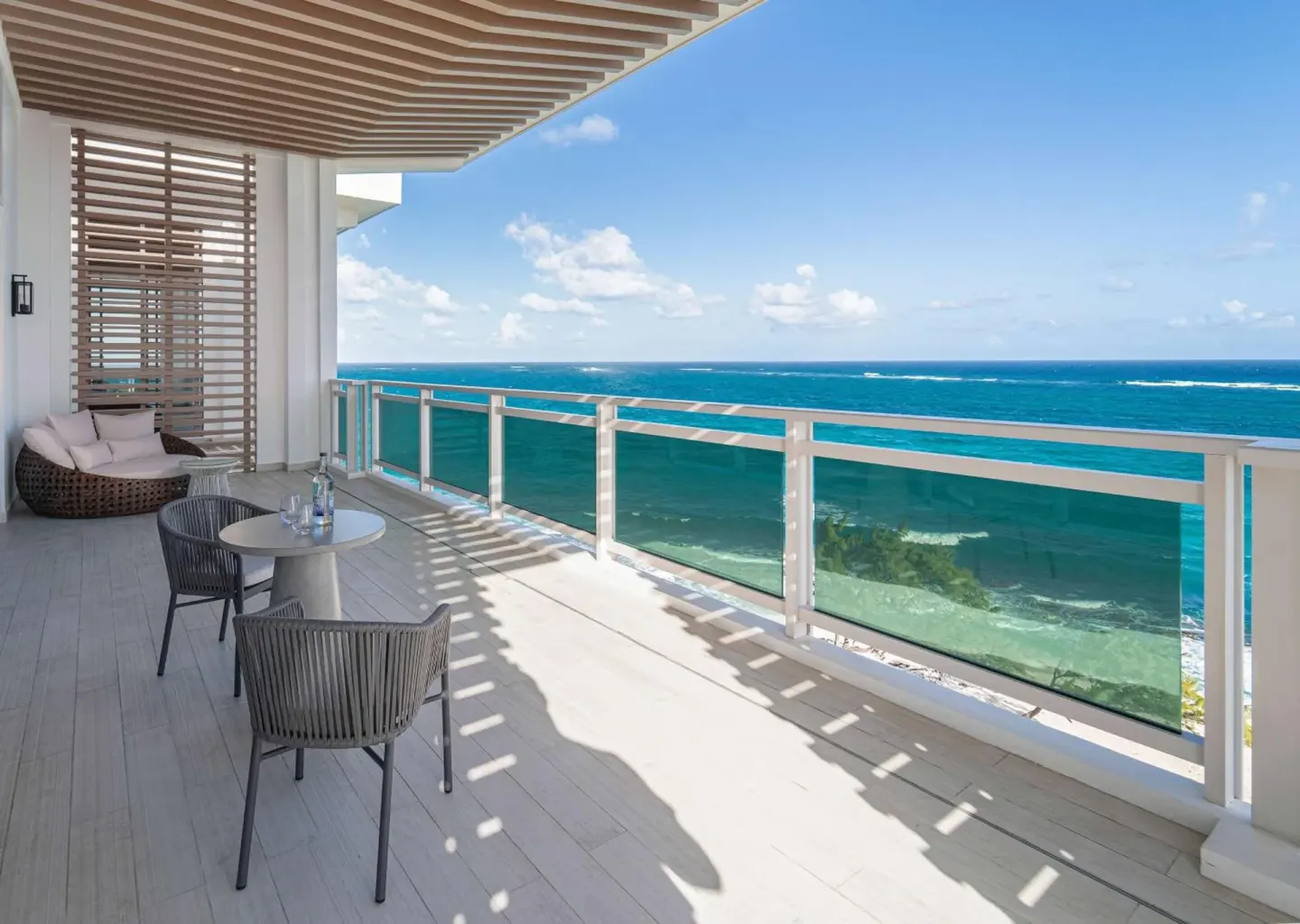 Spacious ocean-view terrace with chairs and glass railing at Wyndham Grand Barbados Sam Lords Castle.