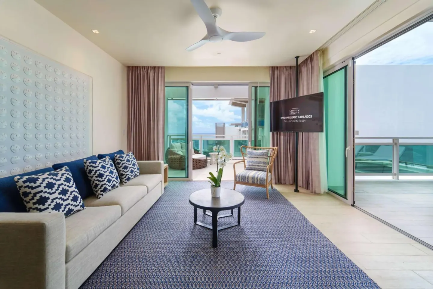 Suite living room with sofa and balcony doors at Wyndham Grand Barbados Sam Lords Castle.