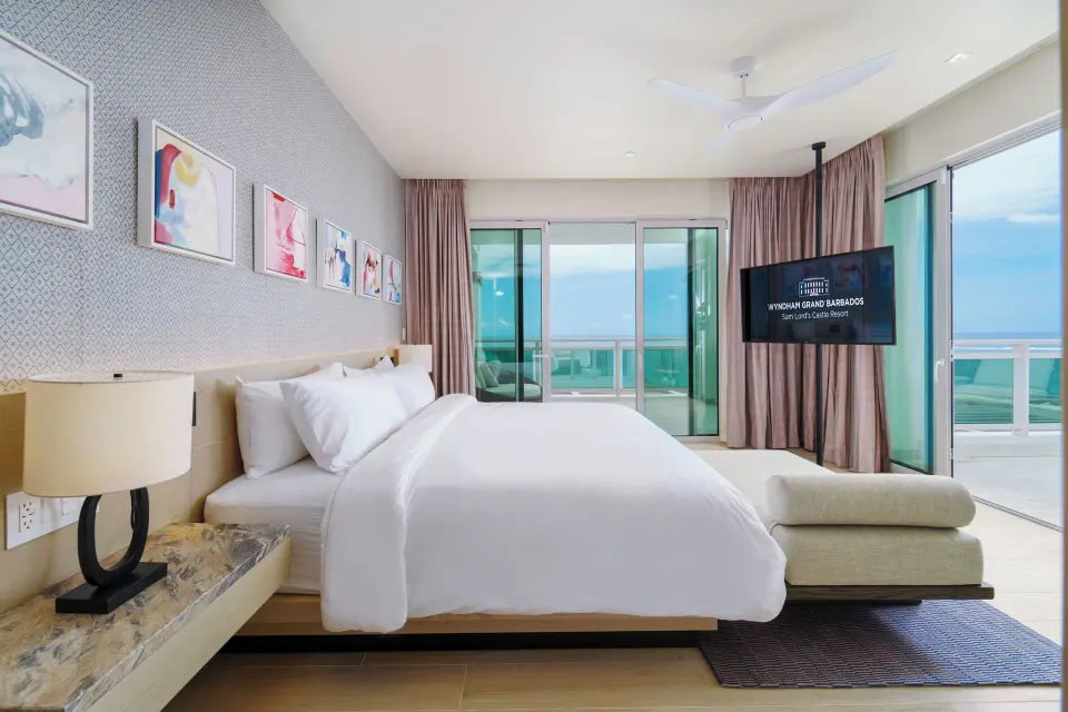 Suite bedroom with king bed and balcony views at Wyndham Grand Barbados Sam Lords Castle.