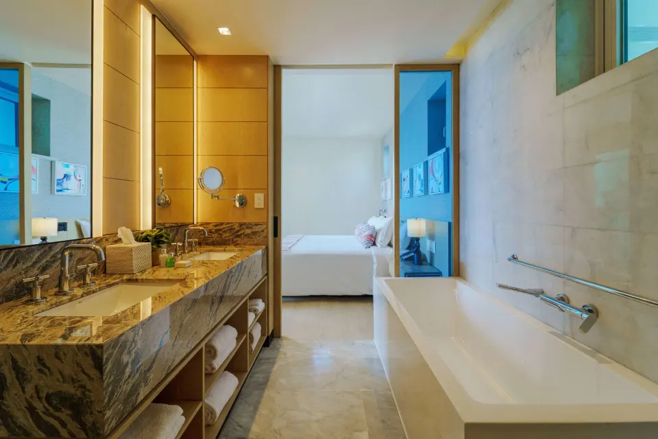 Zephyr Suite bathroom with tub, vanity and bedroom beyond at Wyndham Grand Barbados Sam Lords Castle.