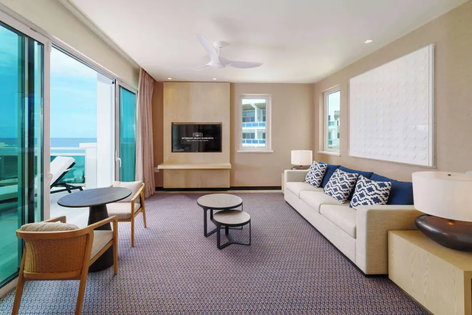 Zephyr Suite living room with sofa and balcony doors at Wyndham Grand Barbados Sam Lords Castle.