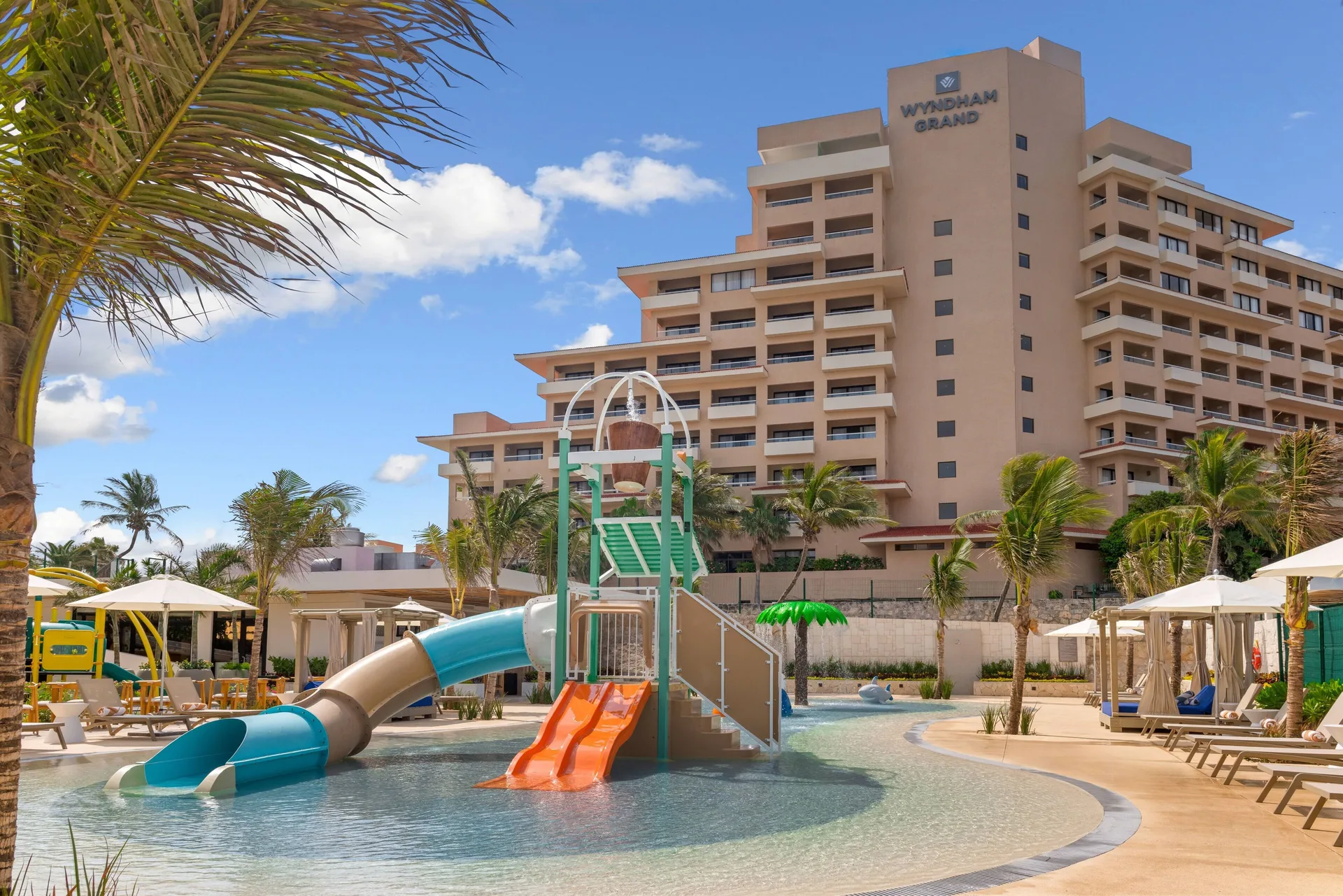 Family pool with waterslides and hotel tower at Wyndham Grand Cancun Resort & Villas.