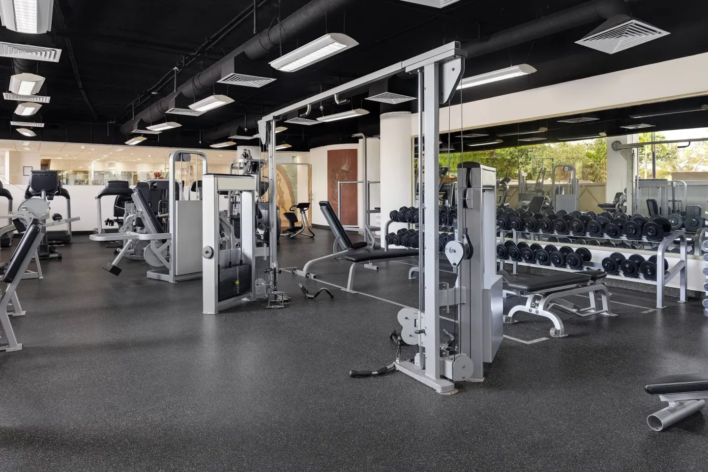 Fitness center at Wyndham Grand Cancun Resort & Villas with weight machines, benches, and dumbbells.