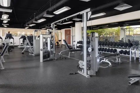 Fitness center at Wyndham Grand Cancun Resort & Villas with weight machines, benches, and dumbbells.