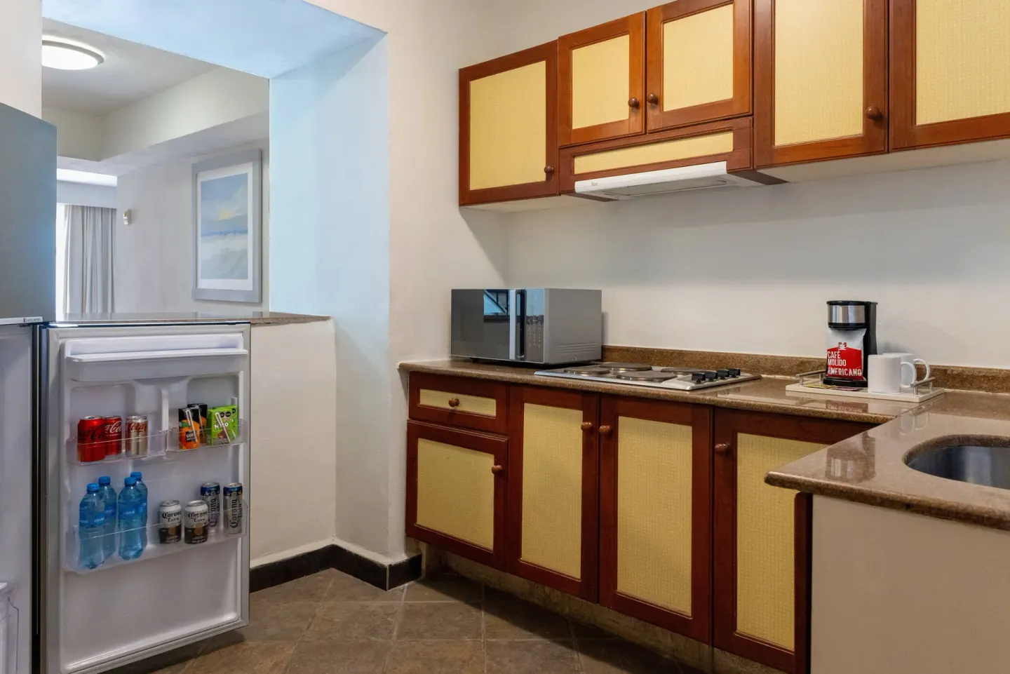 In-room kitchenette with open refrigerator at Wyndham Grand Cancun Resort & Villas.
