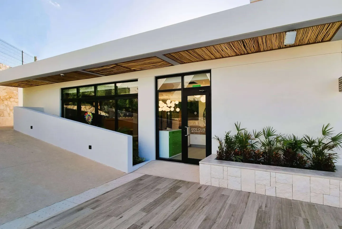 Kids club entrance at Wyndham Grand Cancun Resort & Villas with glass doors and planters.