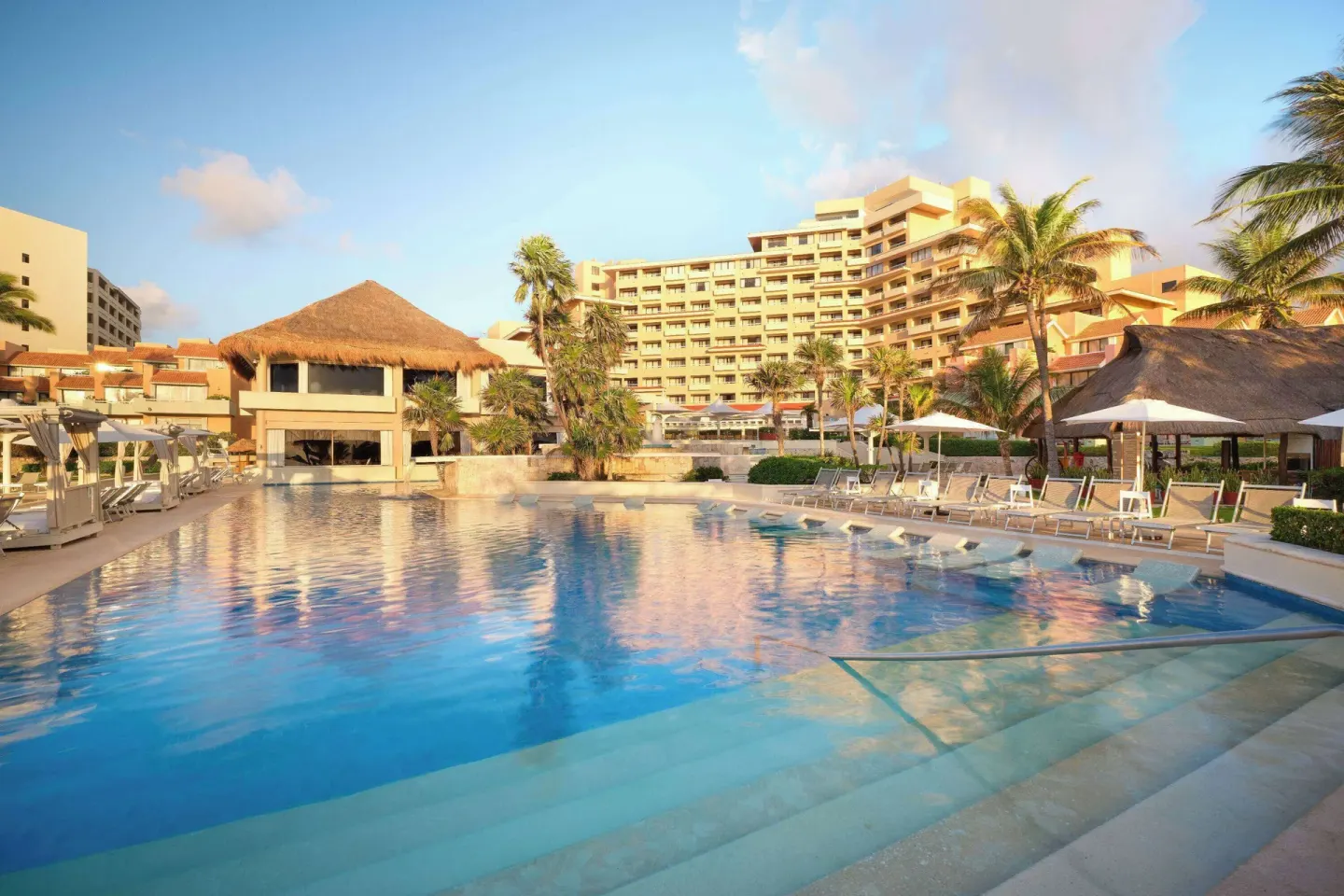 Main pool with resort buildings and palm trees at Wyndham Grand Cancun Resort & Villas.