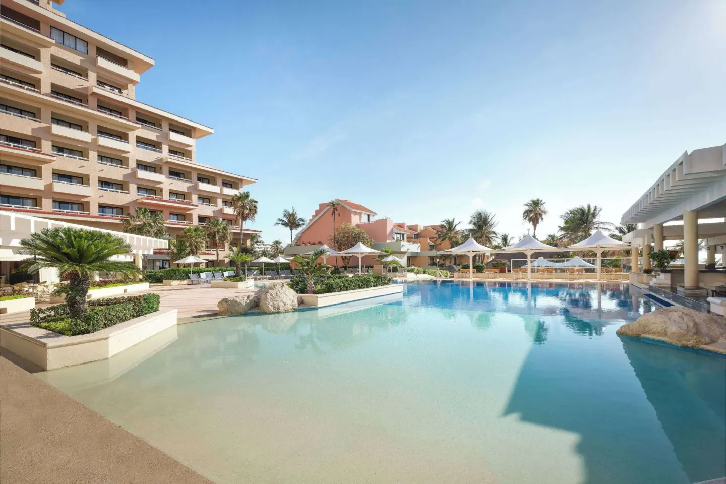 Outdoor pool with umbrellas and resort buildings at Wyndham Grand Cancun Resort & Villas.