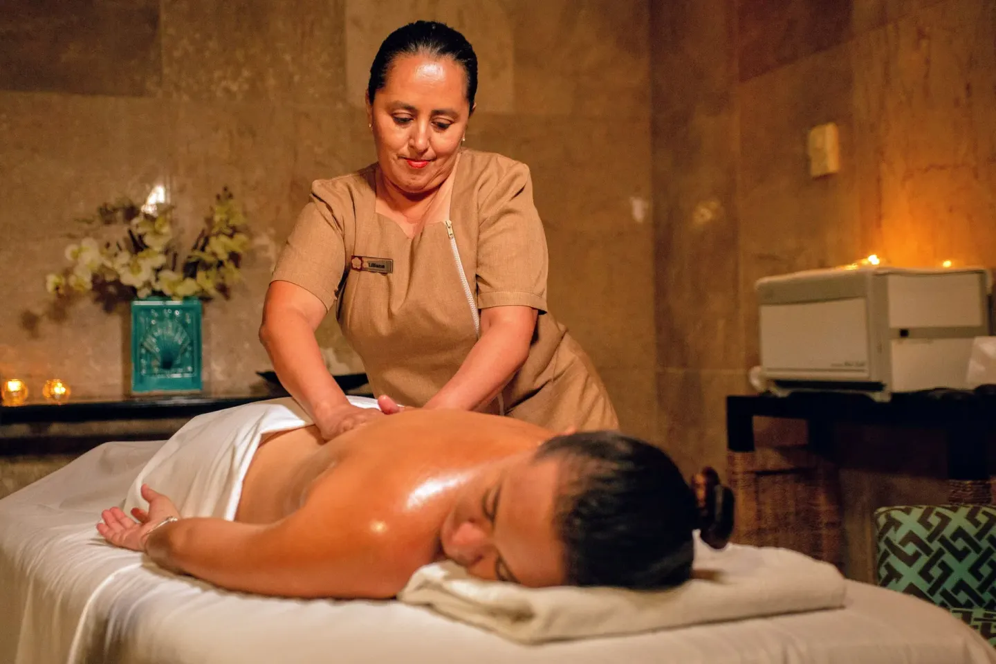 Spa therapist giving a massage at Wyndham Grand Cancun Resort & Villas in a softly lit treatment room.