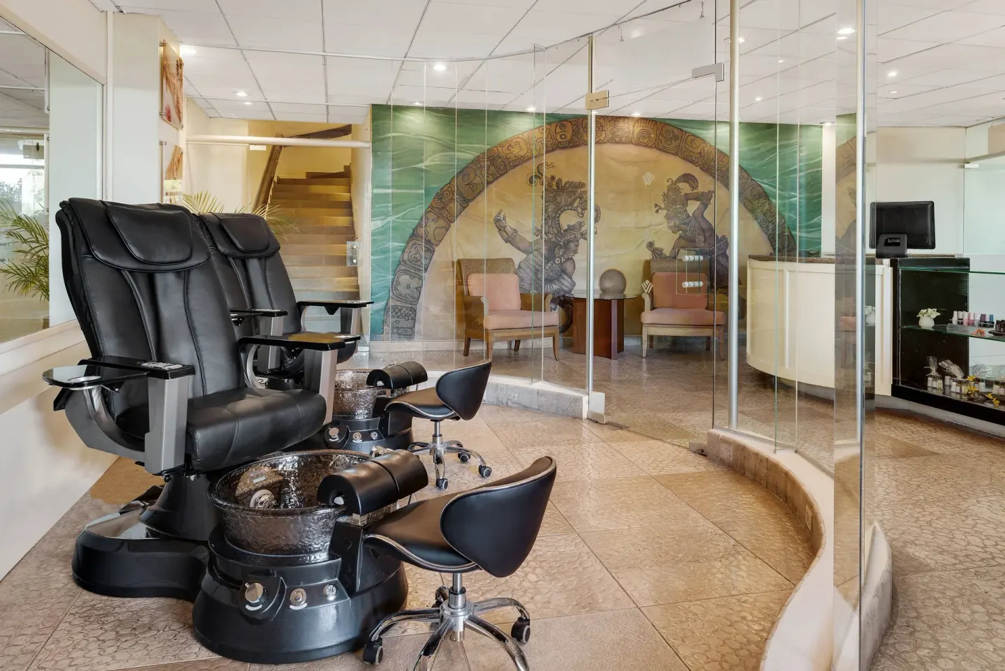Spa pedicure chairs at Wyndham Grand Cancun Resort & Villas beside glass partitions and a mural wall.