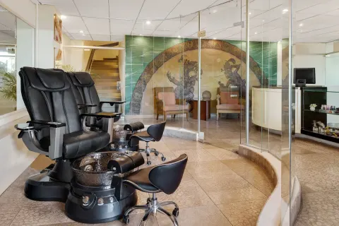 Spa pedicure chairs at Wyndham Grand Cancun Resort & Villas beside glass partitions and a mural wall.