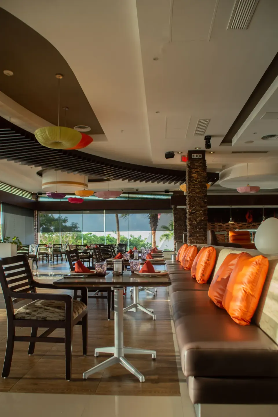 Dining room with orange cushions and set tables at Wyndham Grand Cancun Resort & Villas.