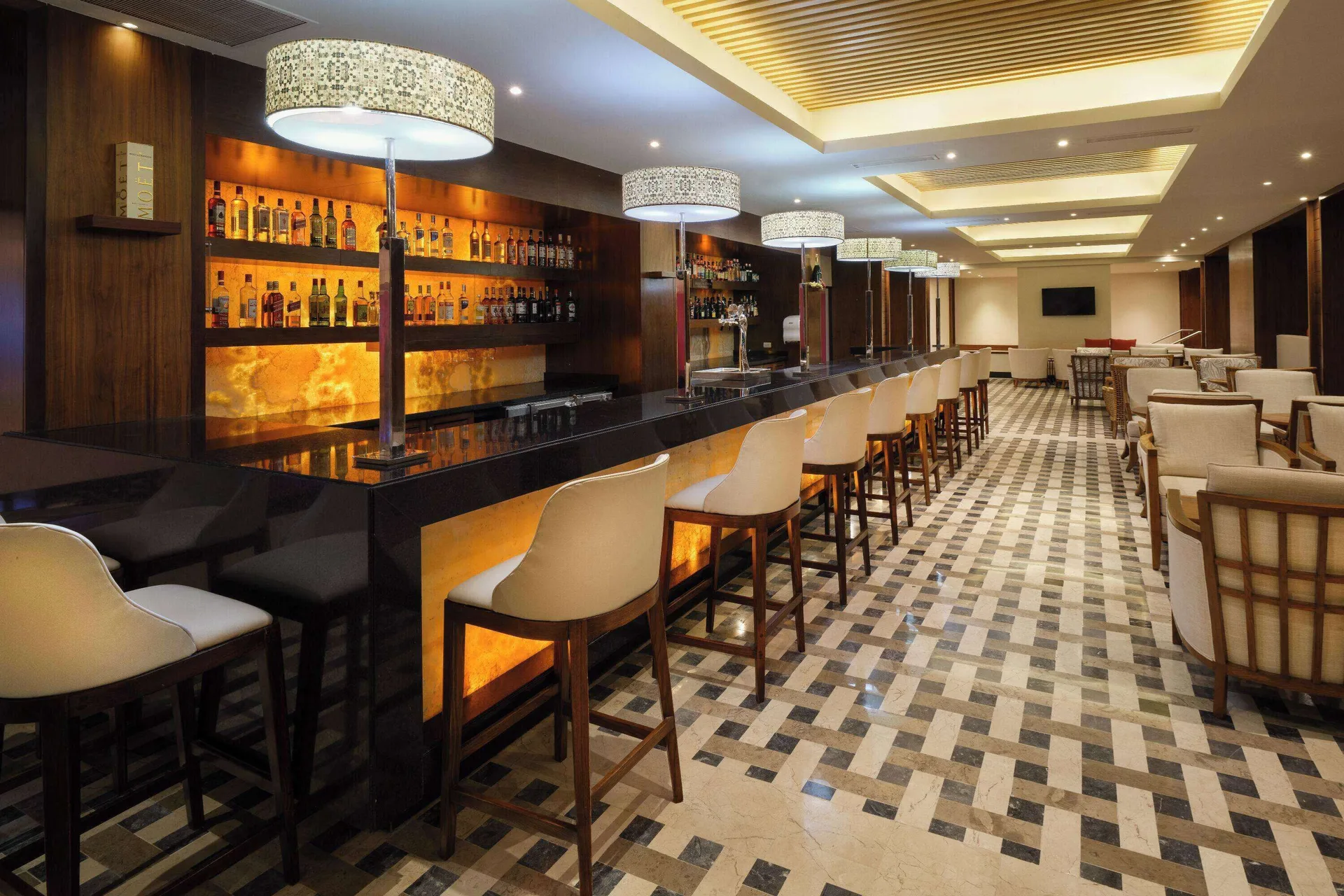 Long bar with stools and lounge seating at Wyndham Grand Cancun Resort & Villas.