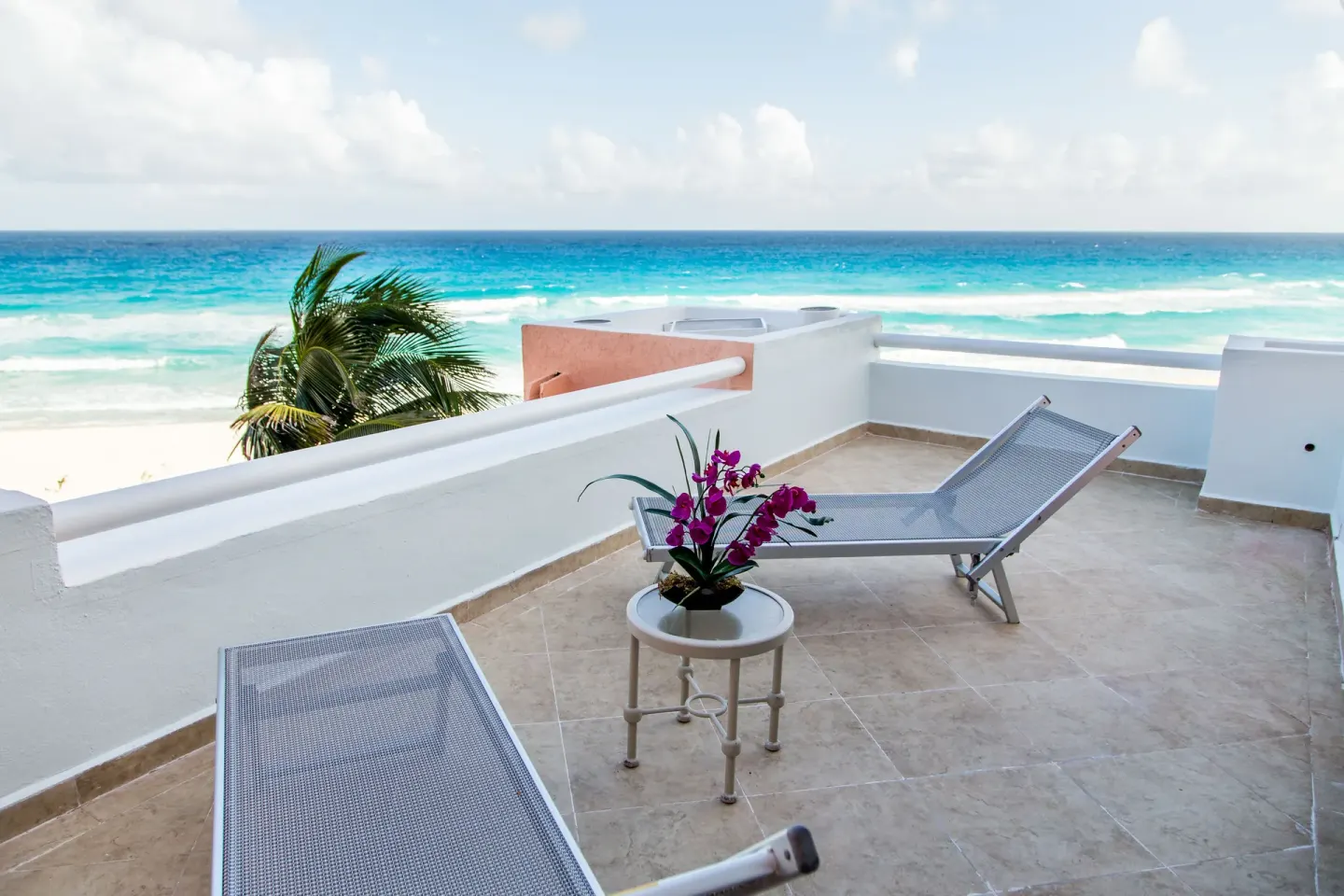 Private terrace with lounge chairs and ocean view at Wyndham Grand Cancun Resort & Villas.