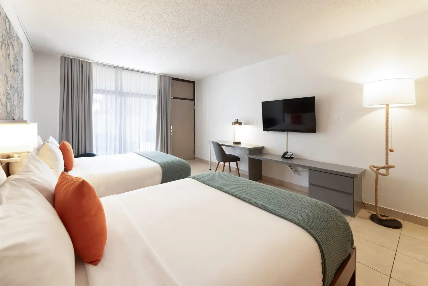 Double queen guest room with desk and wall-mounted TV at Wyndham Palmas Beach and Golf Boutique Resort.
