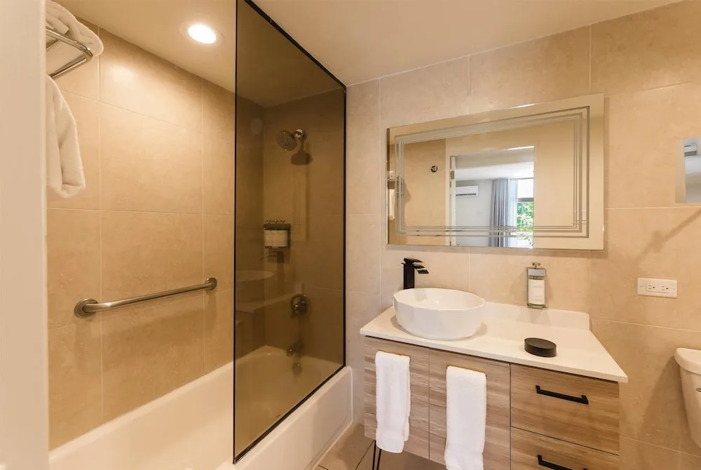 Guest bathroom with glass tub shower at Wyndham Palmas Beach and Golf Boutique Resort.