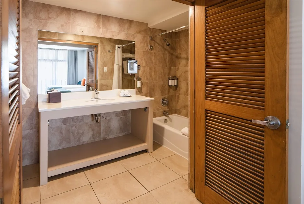 Guest bathroom with open vanity and tub shower at Wyndham Palmas Beach and Golf Boutique Resort.