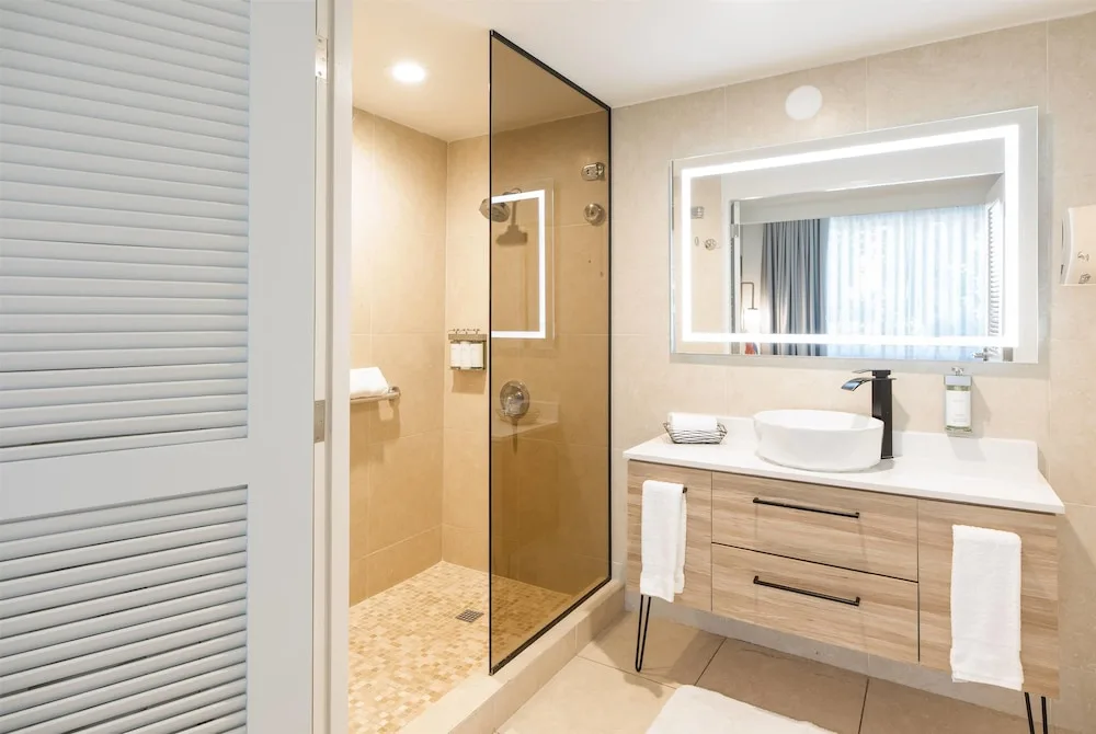 Bathroom with walk-in shower and illuminated mirror at Wyndham Palmas Beach and Golf Boutique Resort.