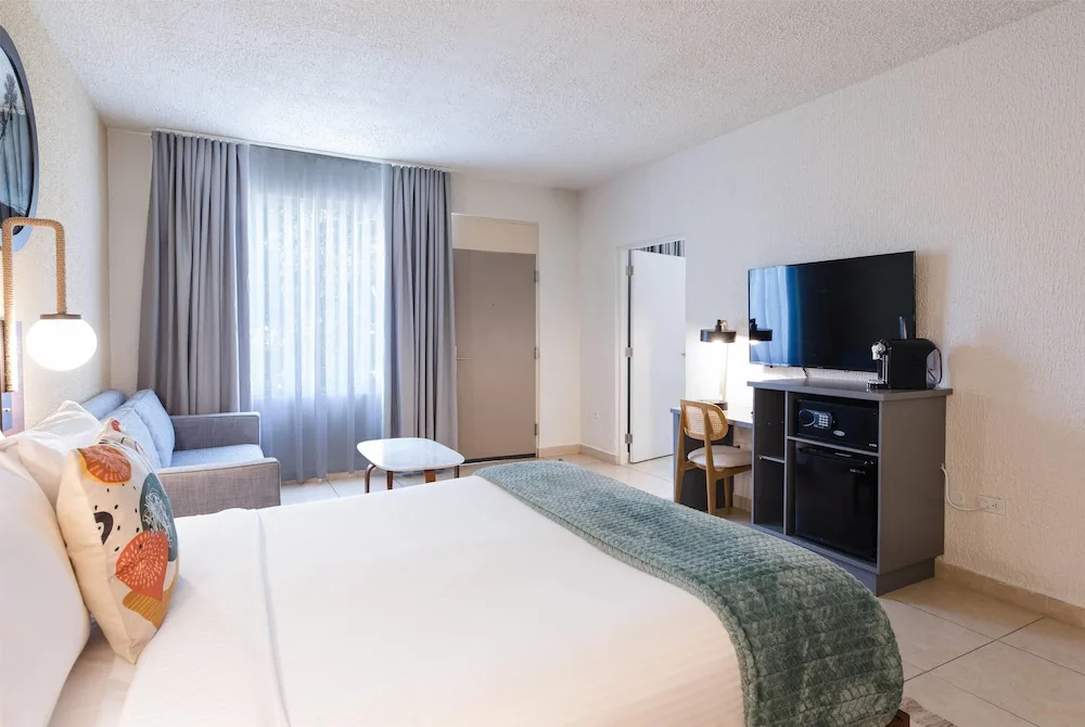 Guest room with king bed, sofa, TV, and coffee station at Wyndham Palmas Beach and Golf Boutique Resort.