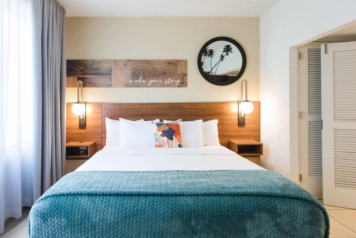 King bed with palm mirror and bedside lights at Wyndham Palmas Beach and Golf Boutique Resort.