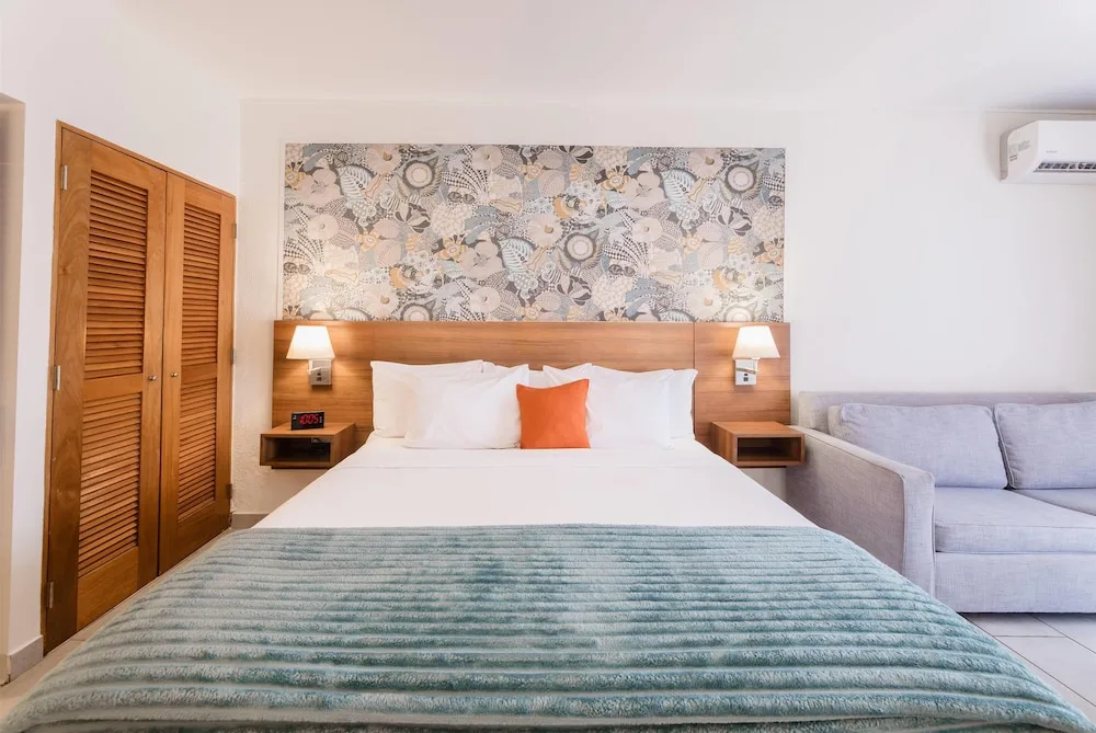 King bed with sofa and patterned headboard wall at Wyndham Palmas Beach and Golf Boutique Resort.