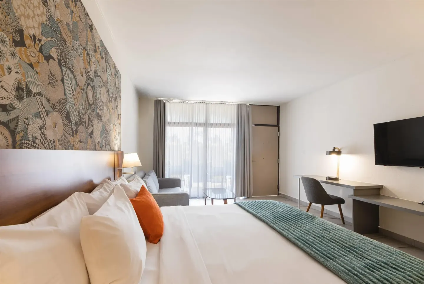 King guest room with desk, sofa, and wall-mounted TV at Wyndham Palmas Beach and Golf Boutique Resort.