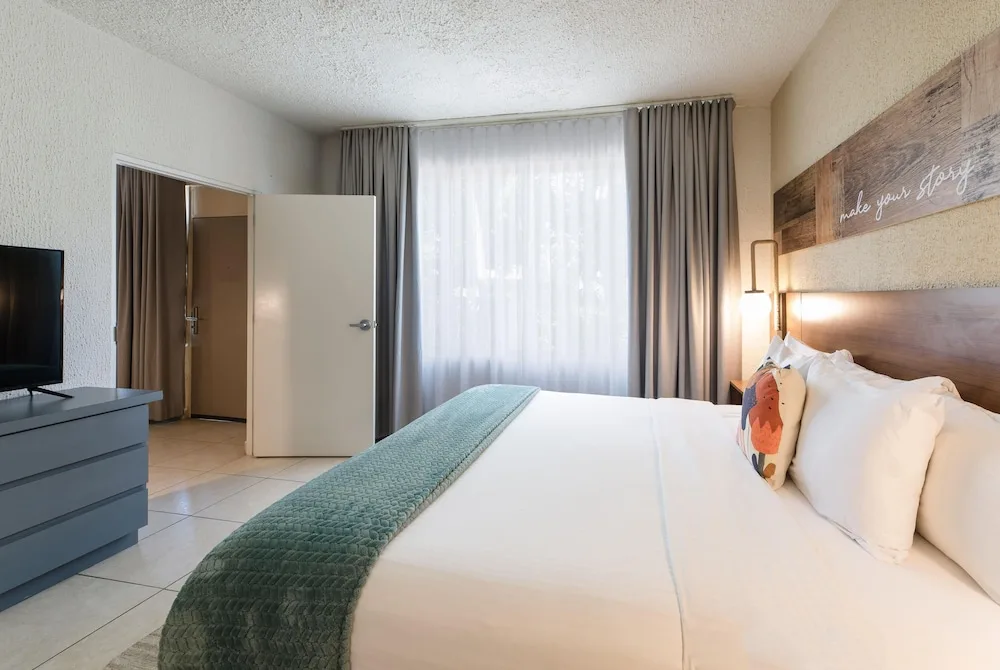 King guest room with TV dresser and curtained window at Wyndham Palmas Beach and Golf Boutique Resort.