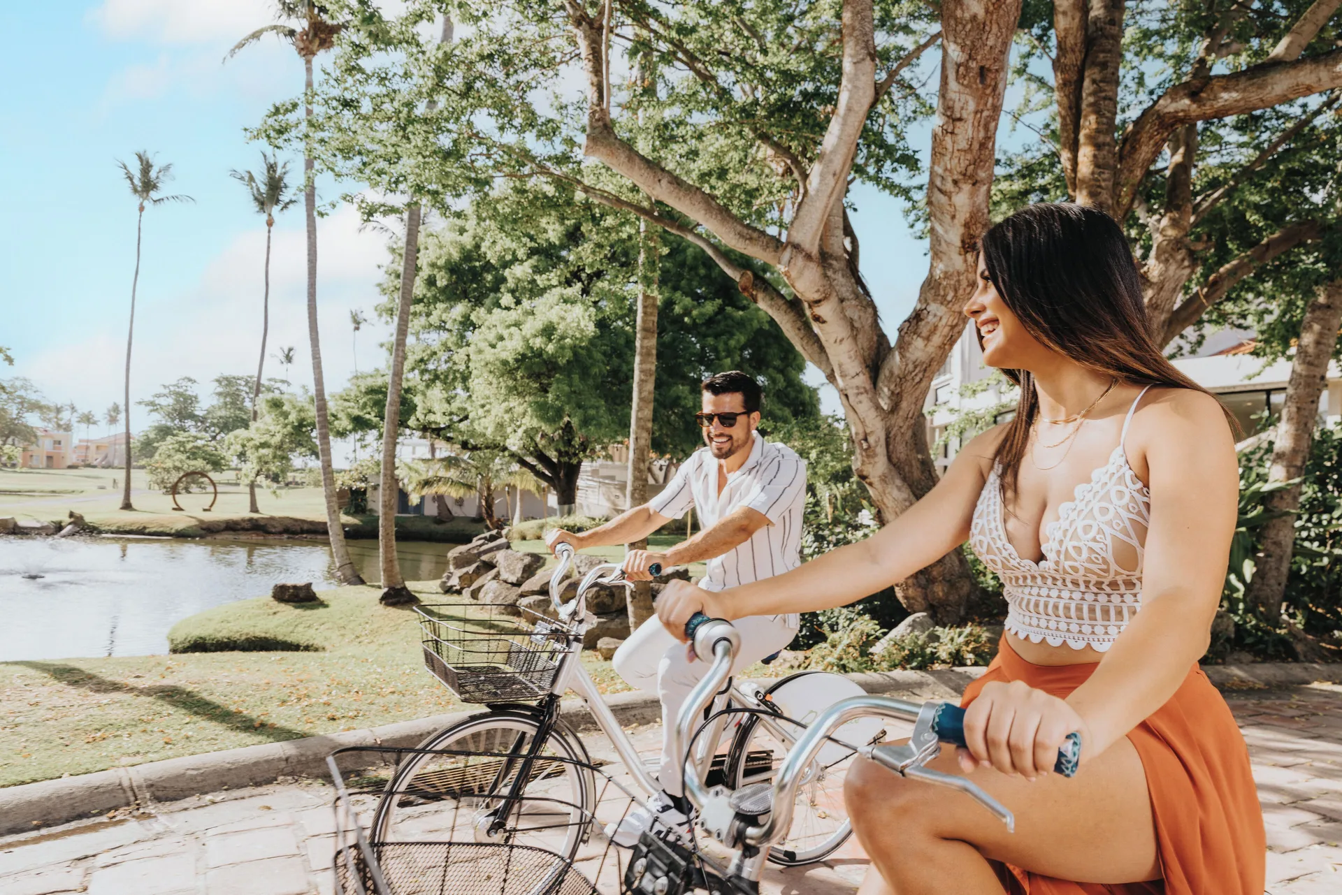 Guests riding bicycles by a lagoon at Wyndham Palmas Beach and Golf Boutique Resort.