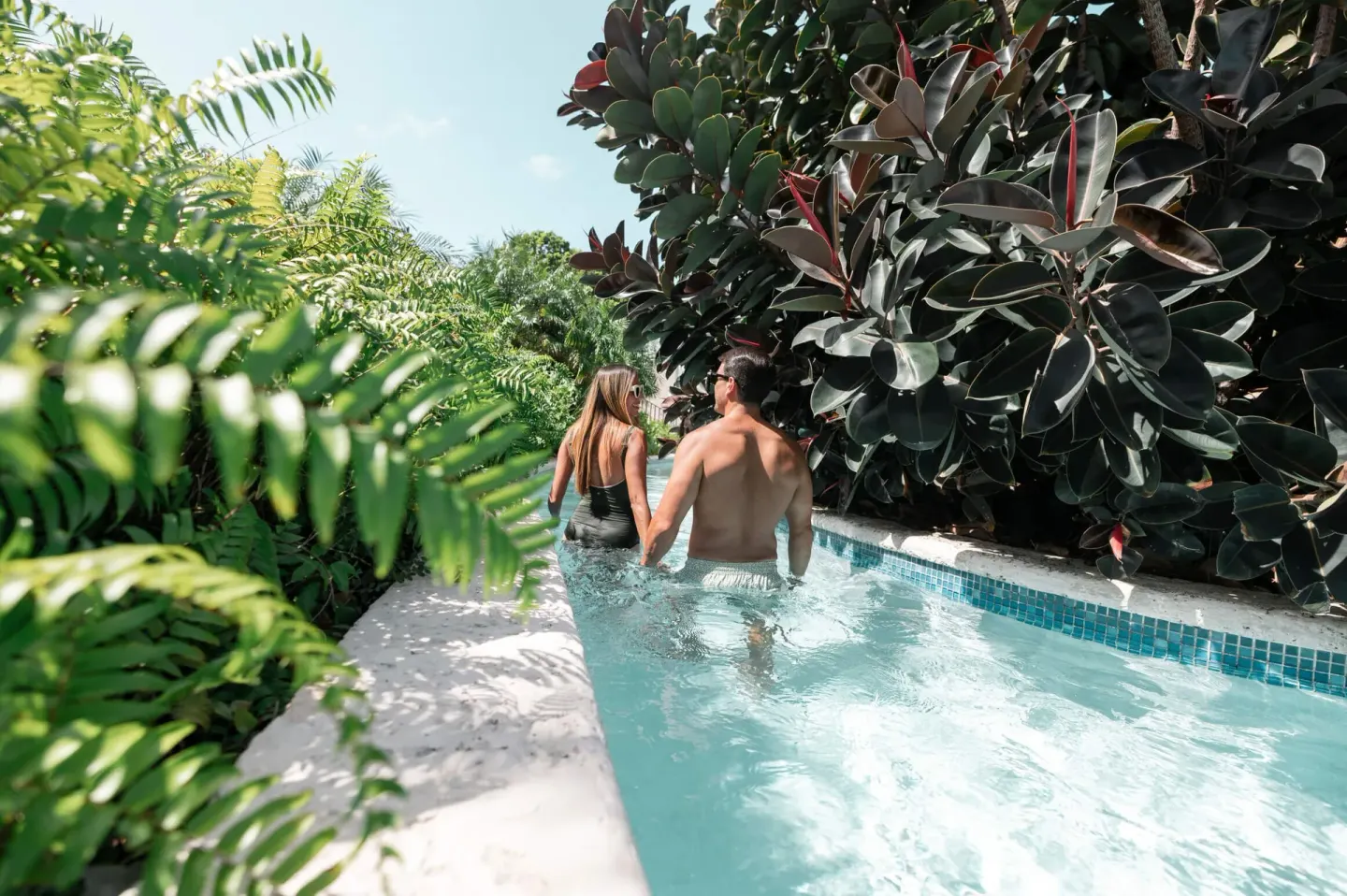Guests wade through a leafy pool channel at Wyndham Palmas Beach and Golf Boutique Resort.