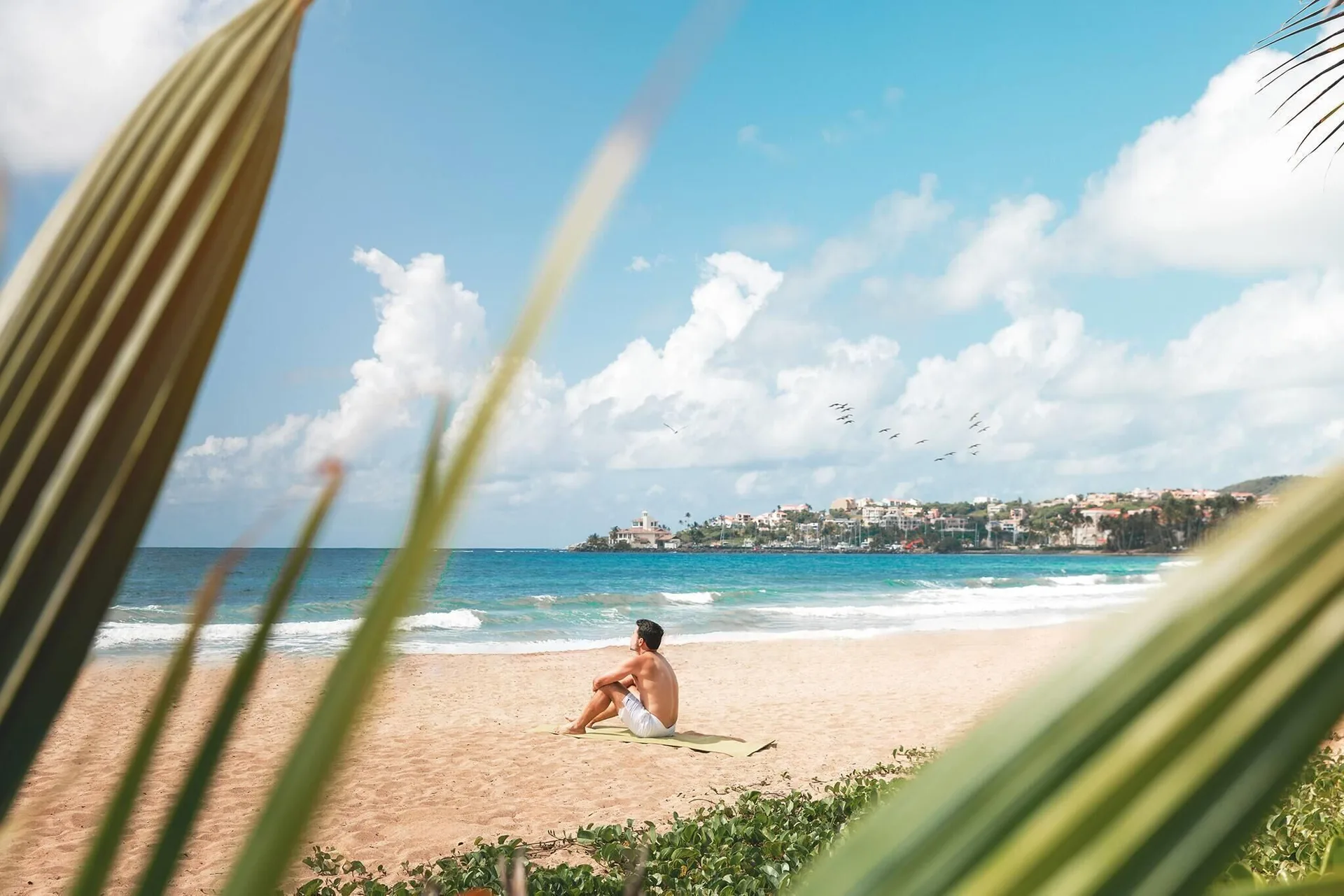 Guest sitting on the sandy beach near Wyndham Palmas Beach and Golf Boutique Resort.