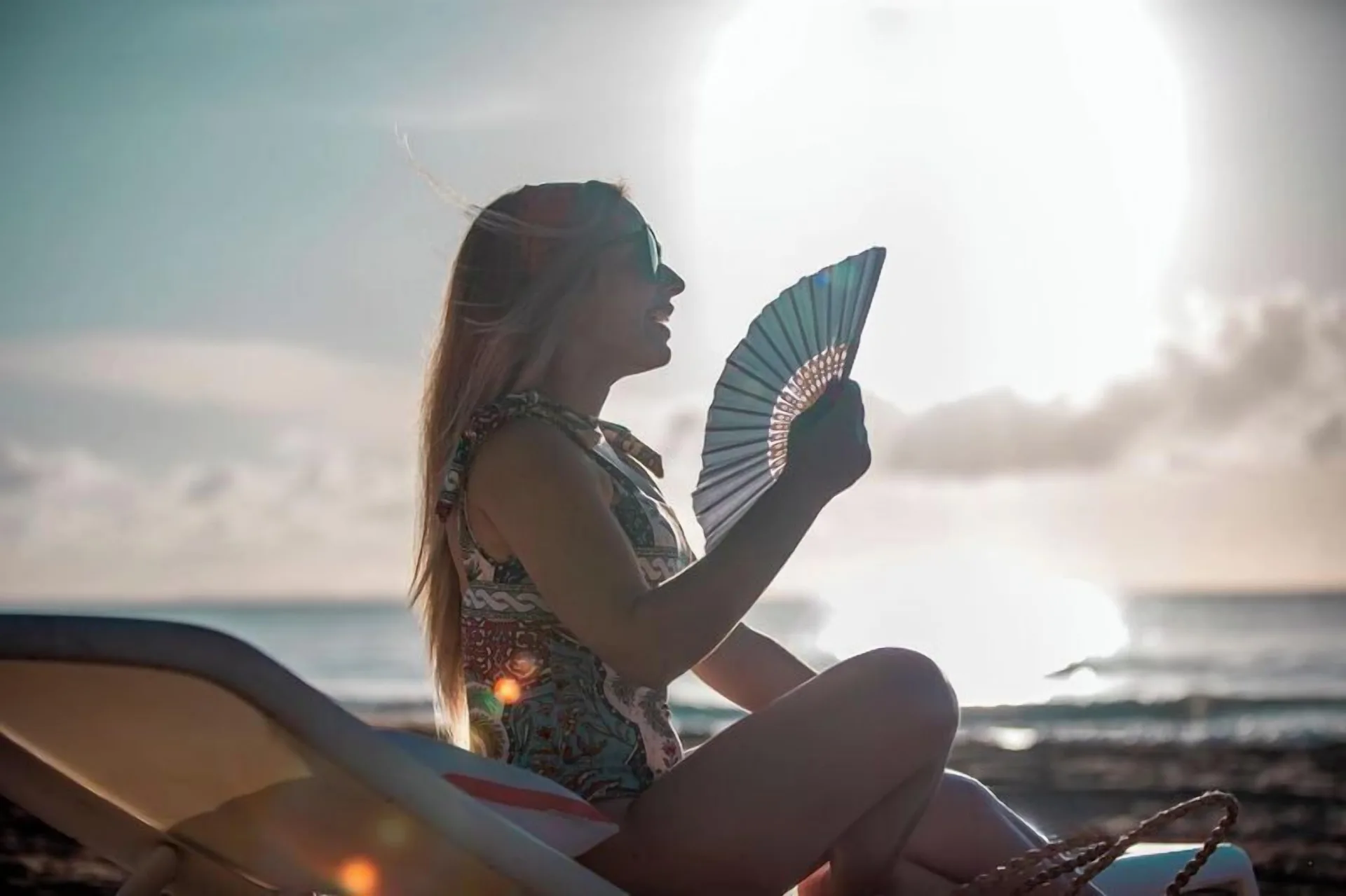 A guest holds a folding fan on a beach lounger at Wyndham Palmas Beach and Golf Boutique Resort.