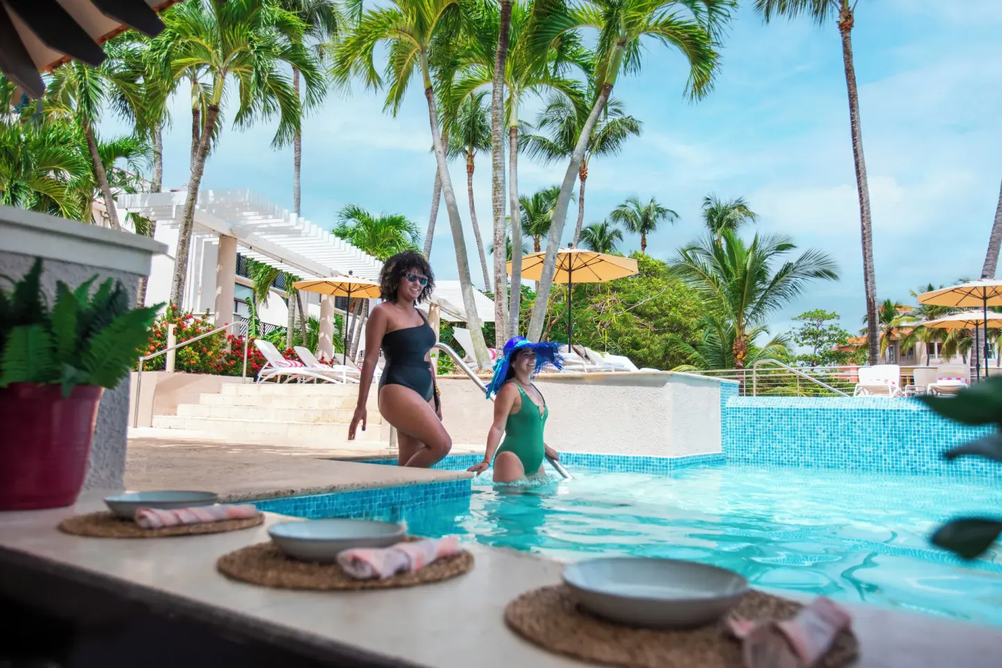 Guests by the pool beside set dining plates at Wyndham Palmas Beach and Golf Boutique Resort.