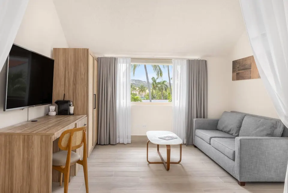 Family Suite Garden View living area with sofa and window at Wyndham Palmas Beach and Golf Boutique Resort.