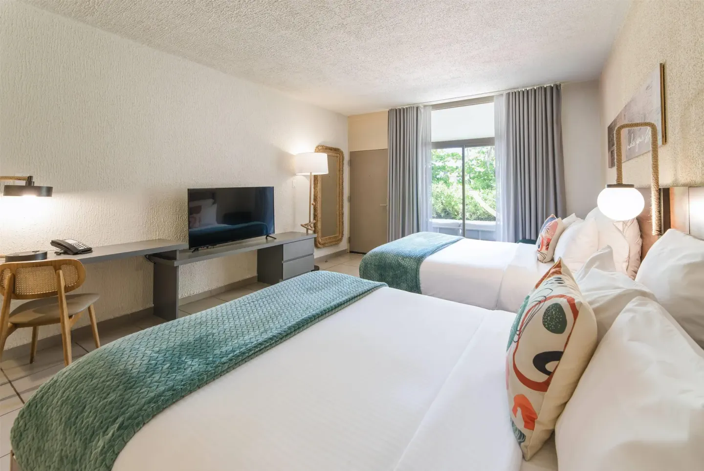 Garden View room with two queen beds, desk, TV, and patio doors at Wyndham Palmas Beach and Golf Boutique Resort.