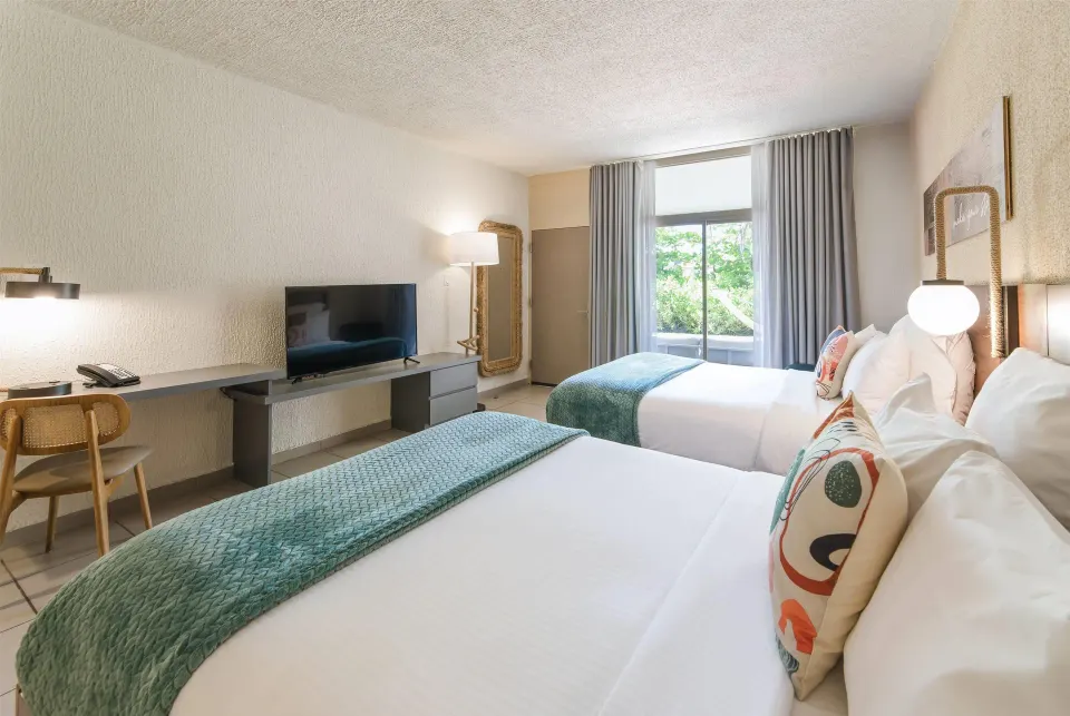 Garden View room with two queen beds, desk, TV, and patio doors at Wyndham Palmas Beach and Golf Boutique Resort.