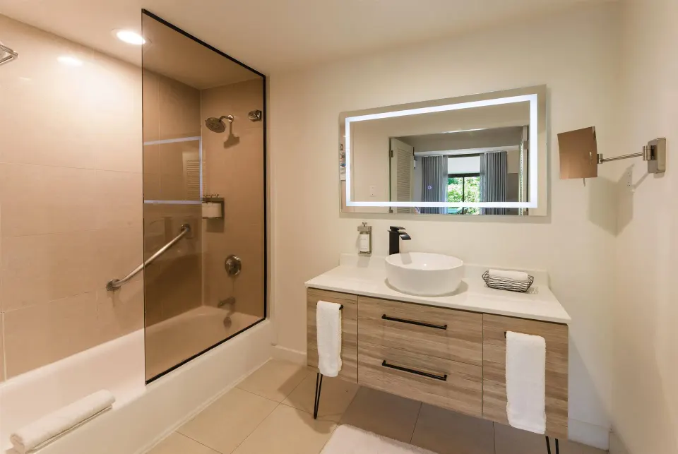 Guest bathroom with illuminated mirror and tub shower at Wyndham Palmas Beach and Golf Boutique Resort.