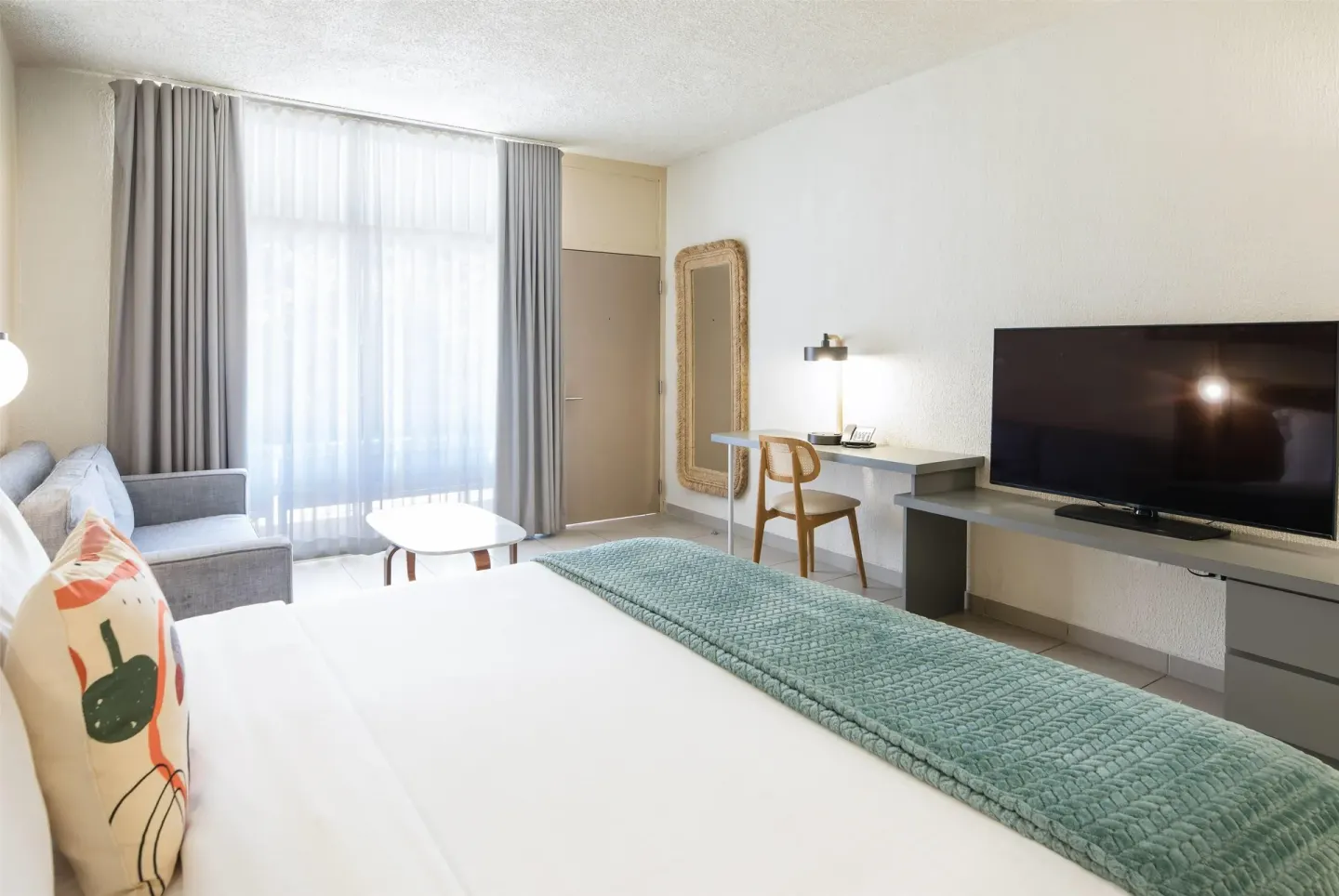 Garden view king room with desk, TV, sofa, and balcony doors at Wyndham Palmas Beach and Golf Boutique Resort.
