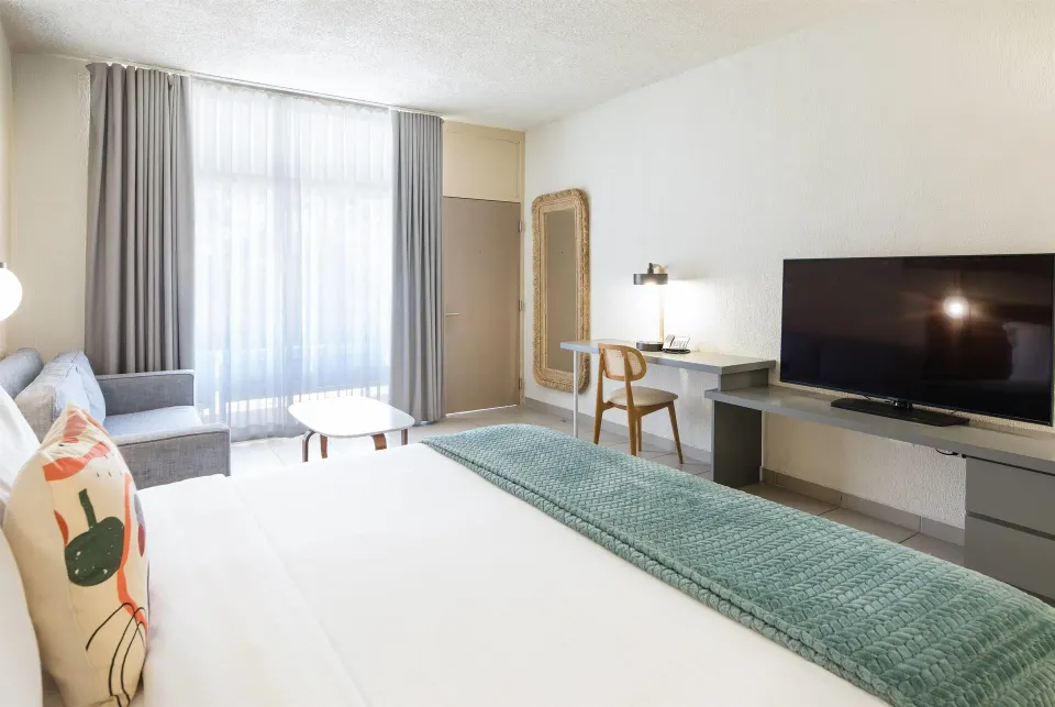 Garden view king room with desk, TV, sofa, and balcony doors at Wyndham Palmas Beach and Golf Boutique Resort.