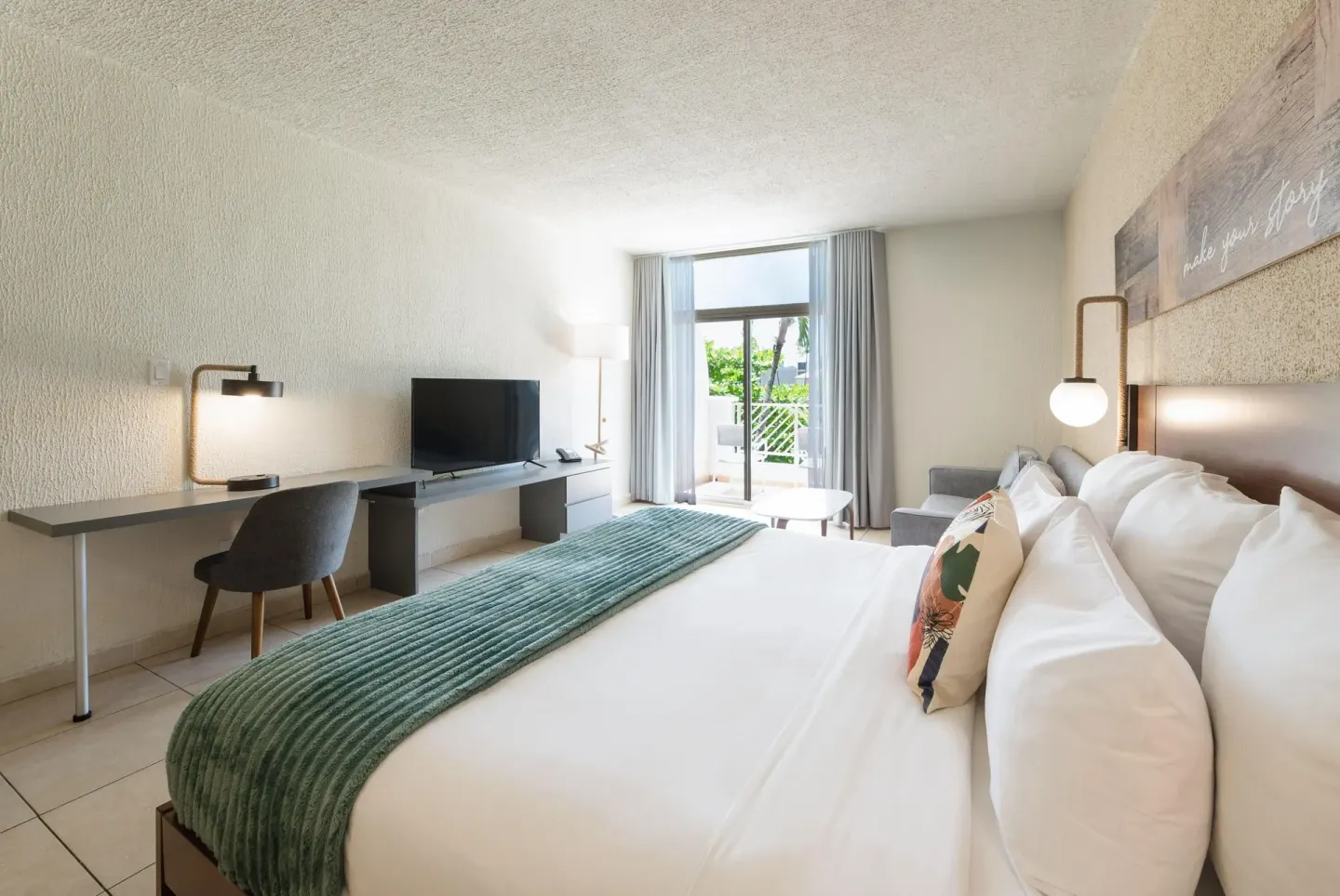 Resort view suite king bed with desk and balcony doors at Wyndham Palmas Beach and Golf Boutique Resort.