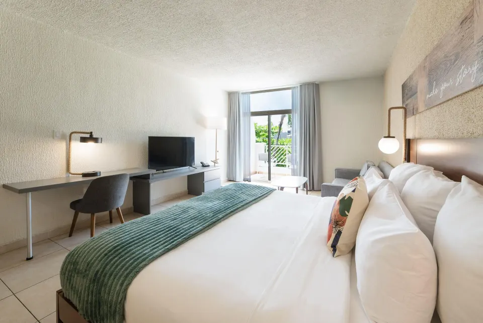 Resort view suite king bed with desk and balcony doors at Wyndham Palmas Beach and Golf Boutique Resort.