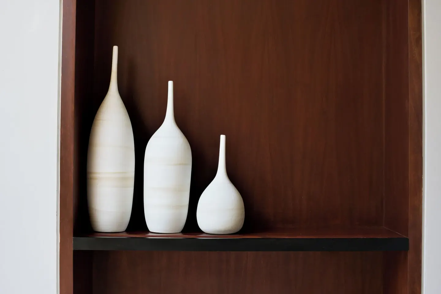 Three white ceramic vases on a wooden shelf at Zadún, a Ritz-Carlton Reserve, Los Cabos.