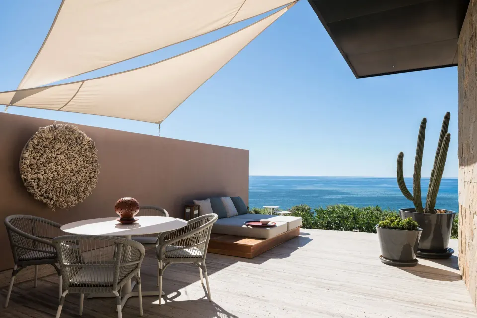 Ocean-view terrace at Zadún, a Ritz-Carlton Reserve, Los Cabos with dining table, daybed, and cactus.