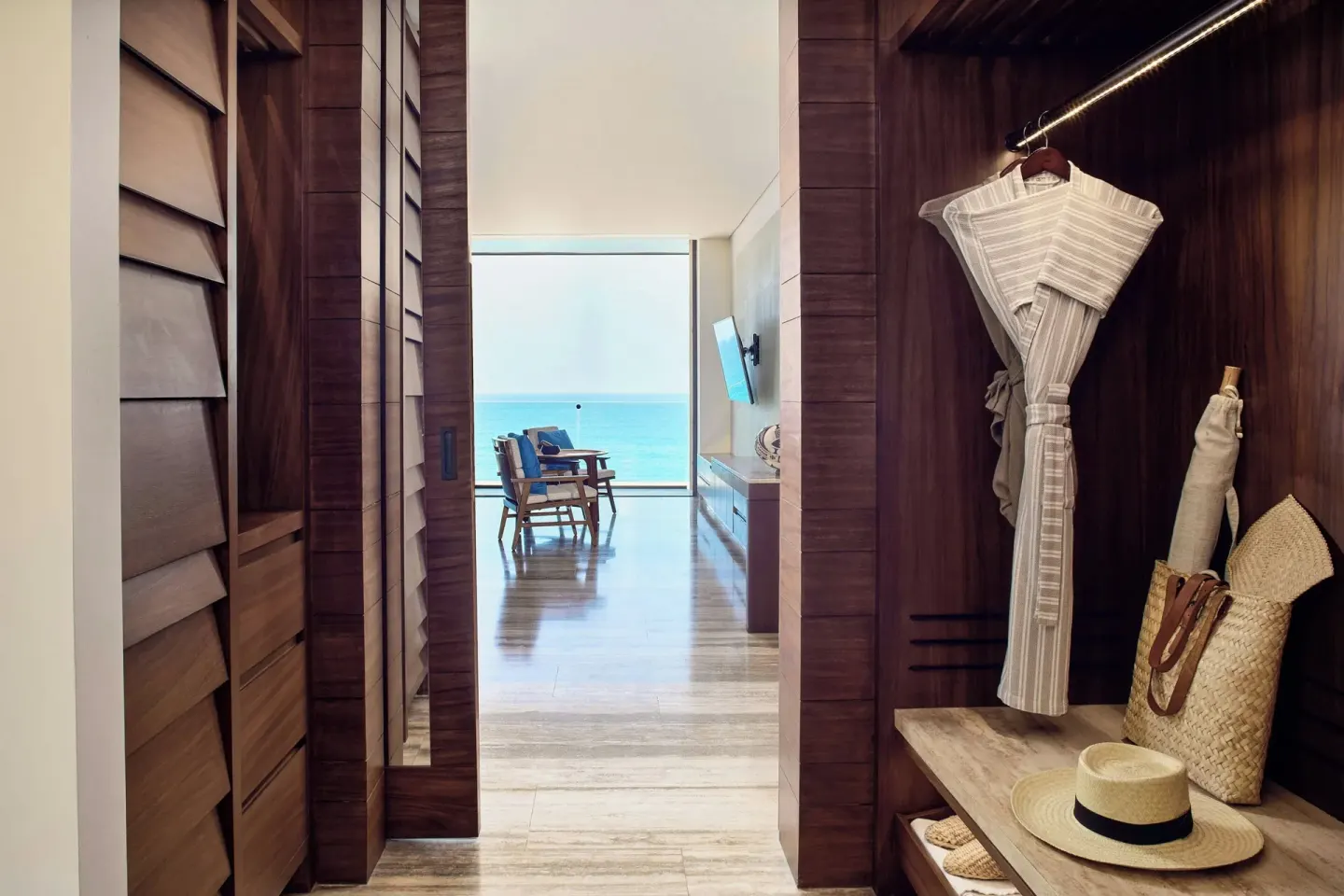 Wooden dressing area with robe and ocean view beyond at Zadún, a Ritz-Carlton Reserve, Los Cabos.